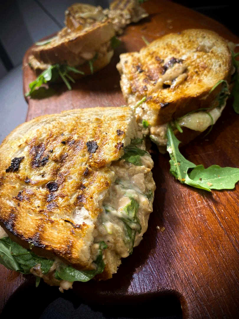 Cheesy pulled smoked chicken sandwich with melted cheese and fresh herbs